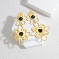 Elegant 18K gold-plated cutout flower tassel earrings with black gemstones on a white stand - Black Stone Flower Style (E745-B)