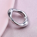 Irregular silver wave-shaped stainless steel ring displayed on soft pink satin fabric - Silver