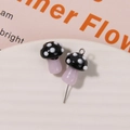 Macro shot of glass mushroom bead with white dots on ceramic plate for DIY jewelry making - No.23 (Black Cap White Dot Pink-Purple Stem)