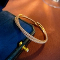 Makro-Detail des doppelreihigen Pavé-Zirkon-Armreifs mit Goldfinish auf Samtschatulle - Kreuz Offener Armreif / Gold