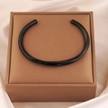 Polished black C-shaped open bangle presented on a jewelry gift box over silk background - Black