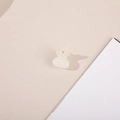 Macro detail of a rabbit-shaped hair clip with inlaid white pearls on a beige surface - Rabbit