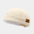 Gros plan d'un bonnet docker beige avec un détail d'écusson en cuir 'DAD' brun - Réglable / Poche zippée