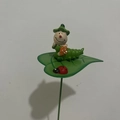 Paletto da giardino con scultura di bruco verde e fiori arancioni su una foglia - Stile Bruco