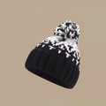 Detail der gestrickten Wintermütze mit gemischtem Bommel und geometrischem Schneeflockenmuster - M / Schwarz