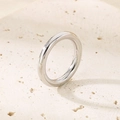 Vertical view of a minimalist silver stainless steel ring on a textured stone surface - US 6 / Thin Plain Band (3mm) / Steel (KR34642-K)