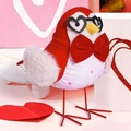 Close-up of cute Valentine bird figurine with heart glasses on pink wooden background - Wearing Bow Tie Bird