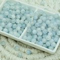 Macro shot of 6mm light blue ice-crackled glass beads in a white ceramic dish - Jade Texture Light Blue (6mm)