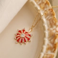 Gold sun necklace with red enamel and zircon on beige ceramic plate macro view - Red Sunburst Style
