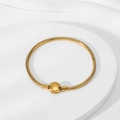 Detail view of 18K gold snake chain bracelet with round clasp on a textured stand - Gold Round Clasp