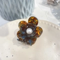 Close-up of tortoiseshell acetate flower hair claw with pearl center on decorative plate - 5.3cm / Blue Tortoise