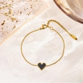 Detailed close-up of golden necklace chain with heart pendant and K15 tag on stone surface - Bracelet / Black Mother of Pearl