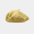 Detail of a bright yellow wool beret featuring a round silver metal emblem on the side - One Size / Yellow