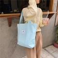 Light blue canvas tote bag showing the textured fabric and casual drape on a street model - Light Blue