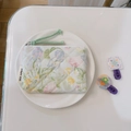 Macro detail of quilted floral coin purse with zipper puller on white porcelain plate - Oil Painting Green Pink Floral