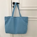 Detail view of large blue canvas tote bag hanging on door showing fabric texture - Solid Sky Blue