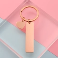 Llaveros de corazón y rectángulo en oro rosa sobre fondo pastel geométrico - Oro rosa