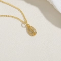 Detailed close-up of a gold rugby-shaped pendant necklace featuring inlaid zircon stones - Conch Shell (XL2422) / Gold