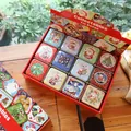 12-pack Christmas tin gift boxes featuring festive illustrations in a display case - Christmas Square Boxes (Pack of 12)