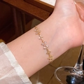 Elegantes goldenes Blumenarmband mit weißen Zirkonia am Handgelenk einer Frau - S743 Gold
