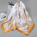 Elegante vierkante sjaal met gouden bloemenprint gedrapeerd over een grijze tas - 90*90cm / Oranje