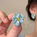 Macro detail of sky blue five-petal flower earrings with a bright yellow gemstone center - 15# Silver Earring Post - Blue