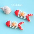Dettaglio di due accessori in resina a forma di lisca di pesce con misura 1,3x3,3cm - Lisca di Pesce Rossa