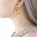 Orecchini retrò a goccia in oro 18K con trama radiale su una modella di profilo laterale - Oro