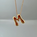 Macro view of gold lava-textured letter M pendant on a delicate link chain necklace - Letter M Single Pendant
