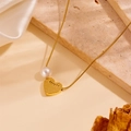 Elegant gold heart and pearl necklace with Beauty engraving on a textured stone background - Heart Pearl Pendant Engraved Style / Gold Necklace