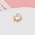Macro detail of a square zircon charm with a gold four-claw setting and double loops - White