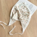 Detail of baby floral headscarf with delicate white lace trim on a rustic wood surface - White