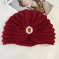 Macro shot of red knit turban hat featuring red teardrop gemstone and pearl accent - Rhinestone Style / Red