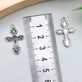 Ciondolo a croce d'argento hip-hop retrò con pietre rosse e blu accanto a un righello - Croce Argento Antico 27x17mm