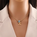 Detail view of gold rope chain with uppercase letter X and blue evil eye bead on a neck - Letter X (N1339)