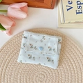 Detail of floral fabric pouch featuring blue heart button on woven mat background - Blue