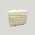 Detail of cream seersucker cosmetic bag showing soft 3D bubble texture and hidden zipper - Ivory