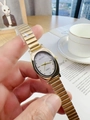 Close-up of a gold oval quartz watch with white dial being held in a lifestyle setting - Gold Band White Dial