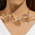 Gros plan du collier feuille de ginkgo dorée avec détails en maille fine et perles - Grand collier fleur creuse doré