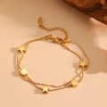 Bracelet double rang chaîne serpent dorée avec pendentifs étoile et cercle sur fond beige - Doré