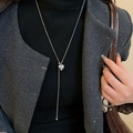 Primo piano di una collana a Y d'argento con ciondolo a cuore su una modella elegante - Stile Ciondolo a Cuore / Argento