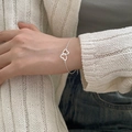 Macro shot of a double heart silver bracelet worn by a model with a white knit cardigan - Double Heart