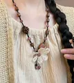 Detail of wooden beads and white woven flower pendant on a bohemian wax rope necklace - Necklace #11 - Black - Brown - Purple