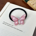 Coletero de mariposa de resina rosa con pedrería sobre páginas de libros antiguos - Coletero / Rosa