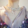 Detailopname van zilveren strik-choker met fonkelende kristallen om de hals - Zilver