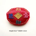 Macro view of Chinese New Year red velvet embroidery patch with gold coins and text - Wealth and Treasure
