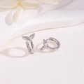 Macro shot of silver mermaid tail earrings on a textured white floral background - Fish Tail