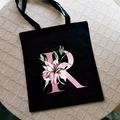 Black canvas tote bag with pink floral letter R print and sturdy shoulder straps - Letter R / Black
