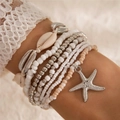 Detail van Boheemse kralenarmbandset met zeester- en schelphangers op wit kantwerk - Armbandenset / Zilveren Set