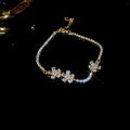 Vista dettagliata del bracciale a fiori placcato oro con pietre di zircone scintillanti - Oro